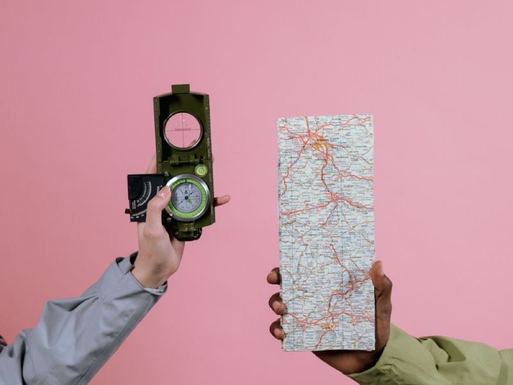 A hand holding a compass over a map